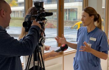 Heidi Stensmyren pratar med journalist framför en kamera