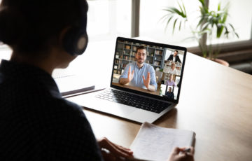 Kvinna sitter framför en laptop, på skärmen syns ett digitalt seminarium